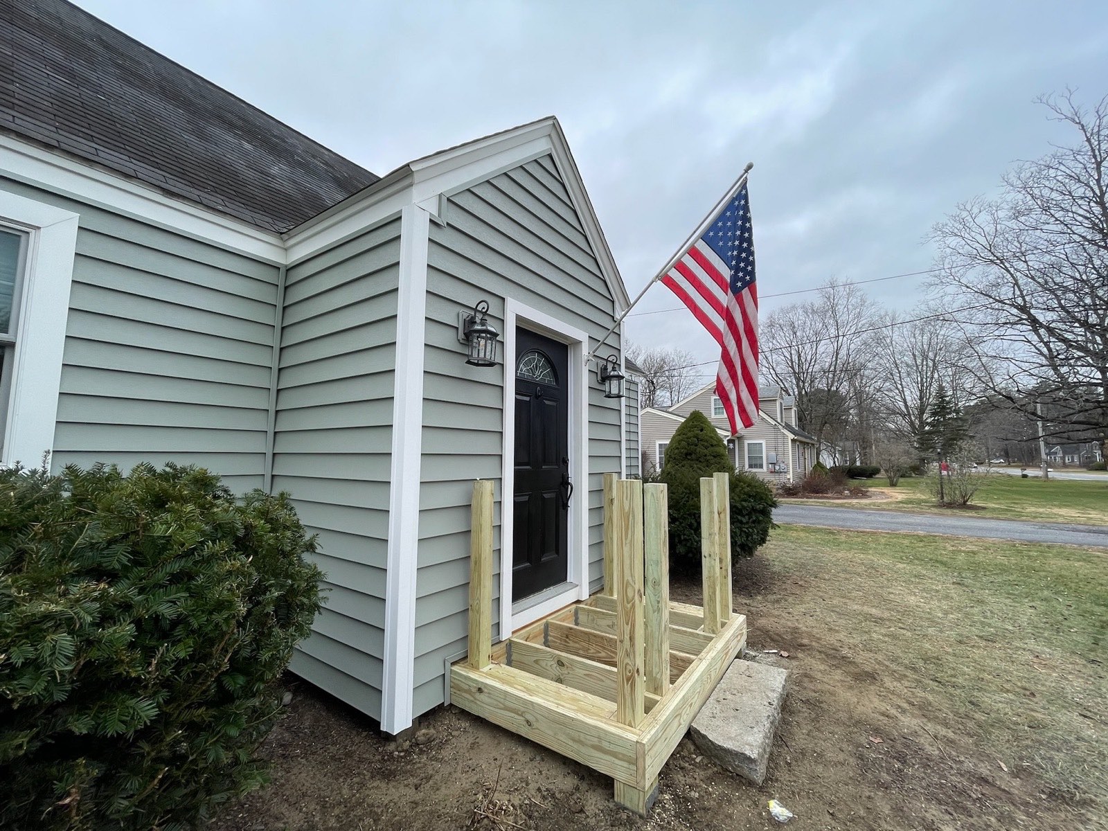 New sage siding, entry door, and porch on a residential home